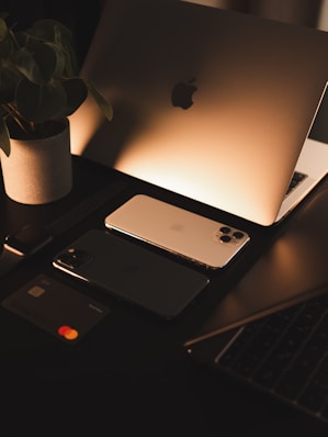 A cozy, modern workspace with a laptop displaying the rva zone online store homepage surrounded by luxury products and gadgets.