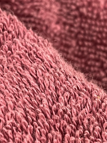 Close-up of soft fabric texture from a premium sweatshirt in muted pink tones