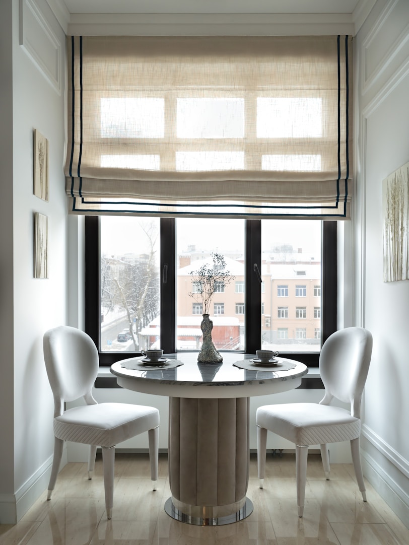 a dining table with chairs and a window with blinds