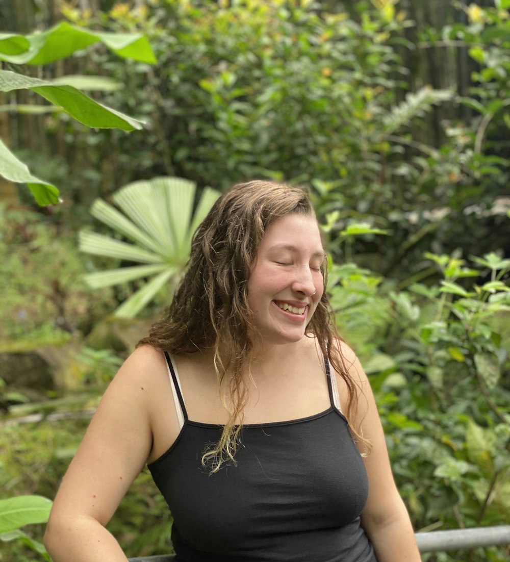 a woman smiling with trees in the background