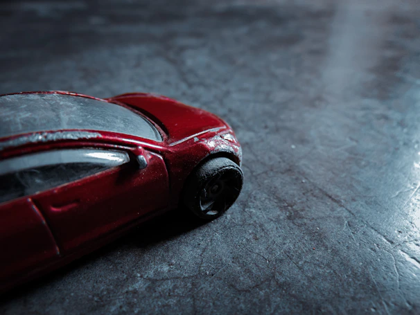 Close-up of a glossy red diecast classic muscle car with detailed chrome accents on a dark metallic background