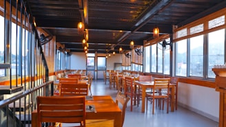 A warmly lit dining area with rustic wooden tables and soft glowing pendant lights creating an inviting atmosphere.