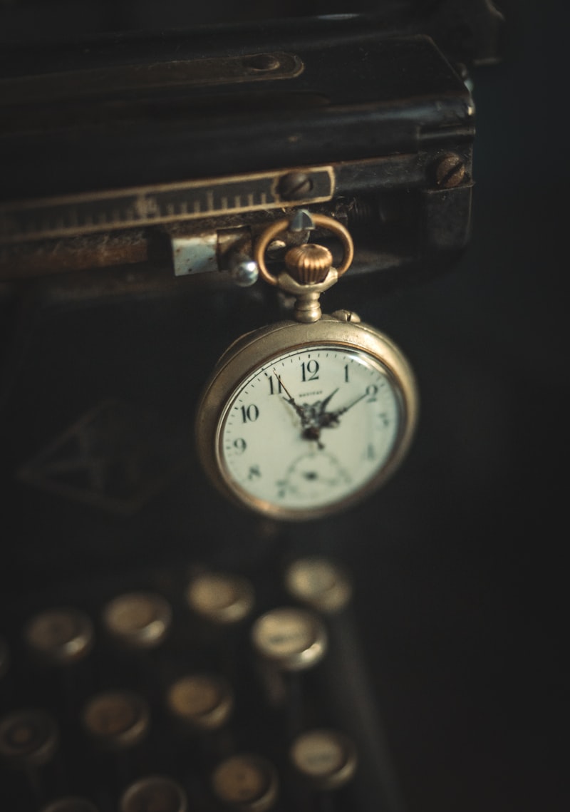 A pocket watch resting near typewriter keys