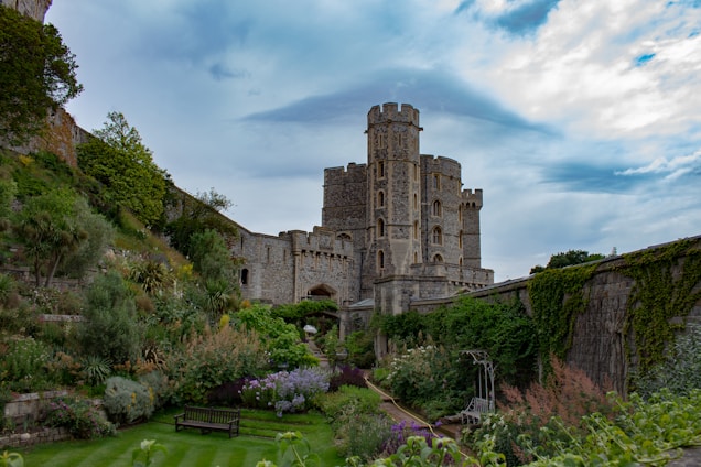 An ancient stone manor surrounded by lush gardens under a golden sunset.