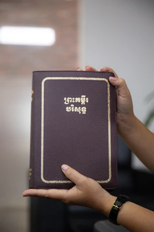 Close-up of hands holding a financial guidebook with a sleek black and beige cover.