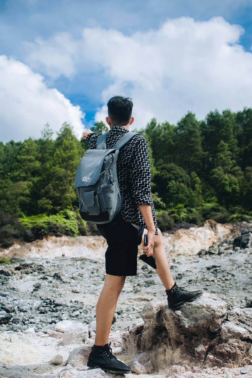 a man with a backpack on a rocky area with trees in the background