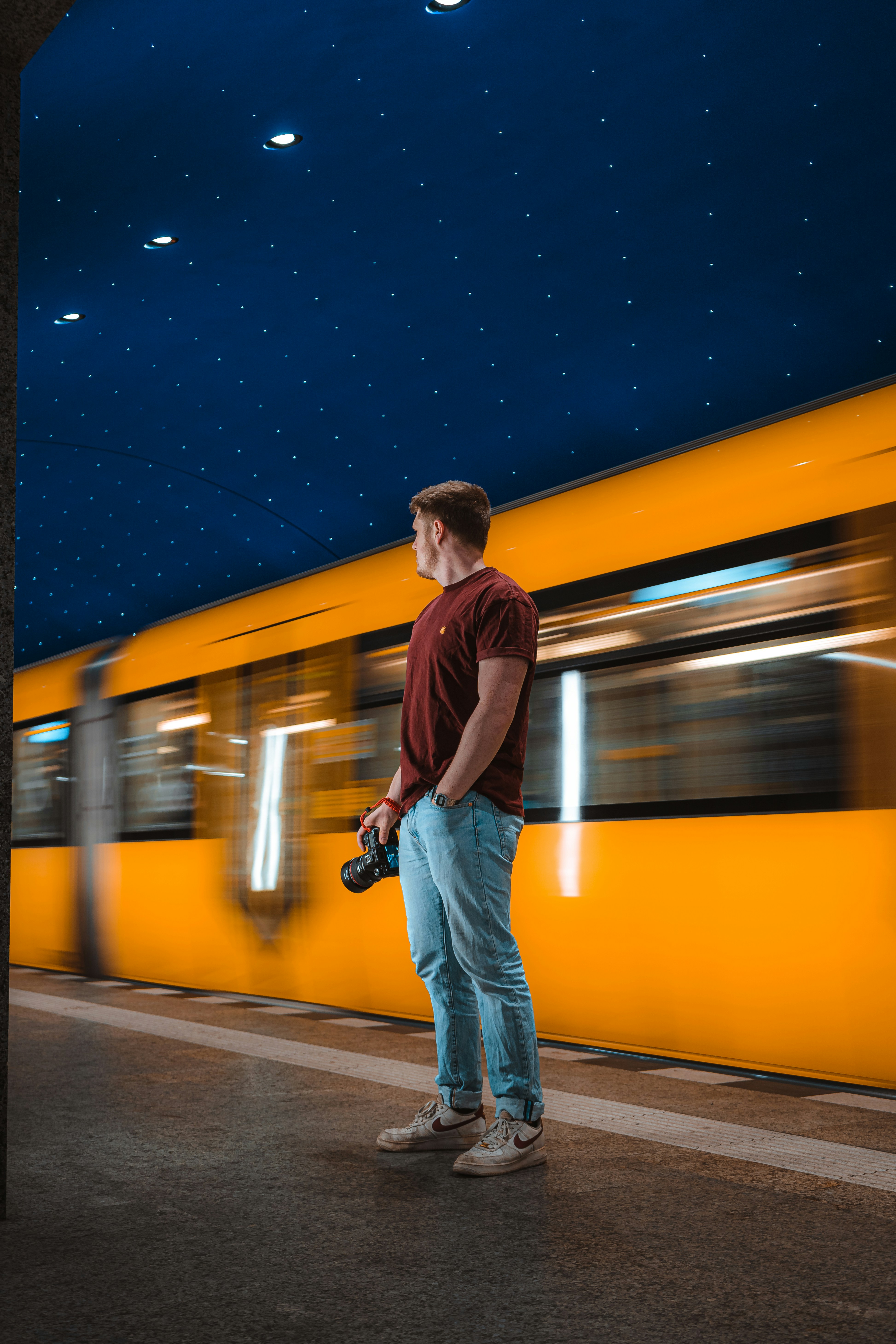 Foto Un hombre parado frente a un tren por la noche – Imagen Berlina ...