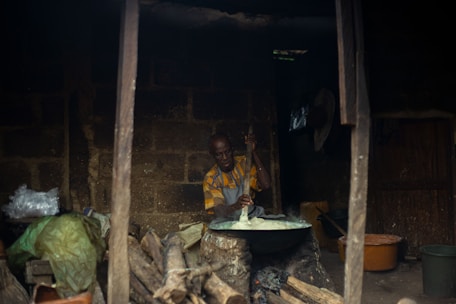 A family member carefully stirring jaggery in a large traditional pan over an open fire.