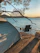 A happy family setting up their tent beside a serene lakeside campground at sunset.