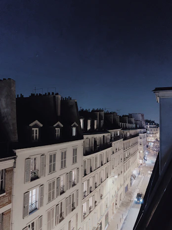 A moody Parisian street at twilight, bathed in soft golden light under a crescent moon.