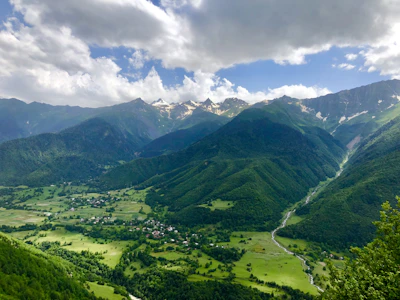 Wide shot of a peaceful valley nestled between towering Himalayan peaks.