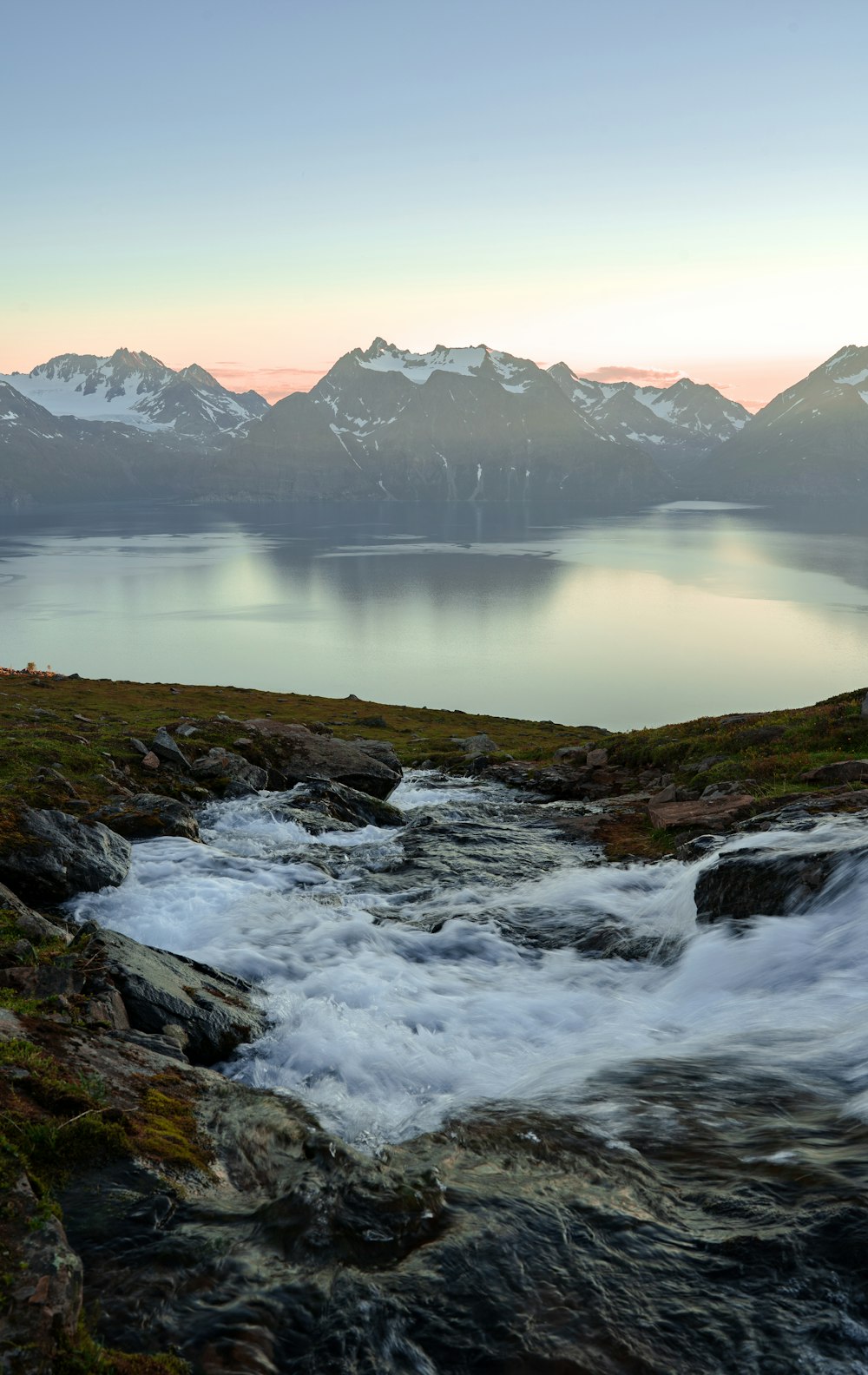 a river flowing through a valley with mountains in the background