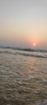 A serene beach scene with gentle waves and soft breeze under a pastel sunset.