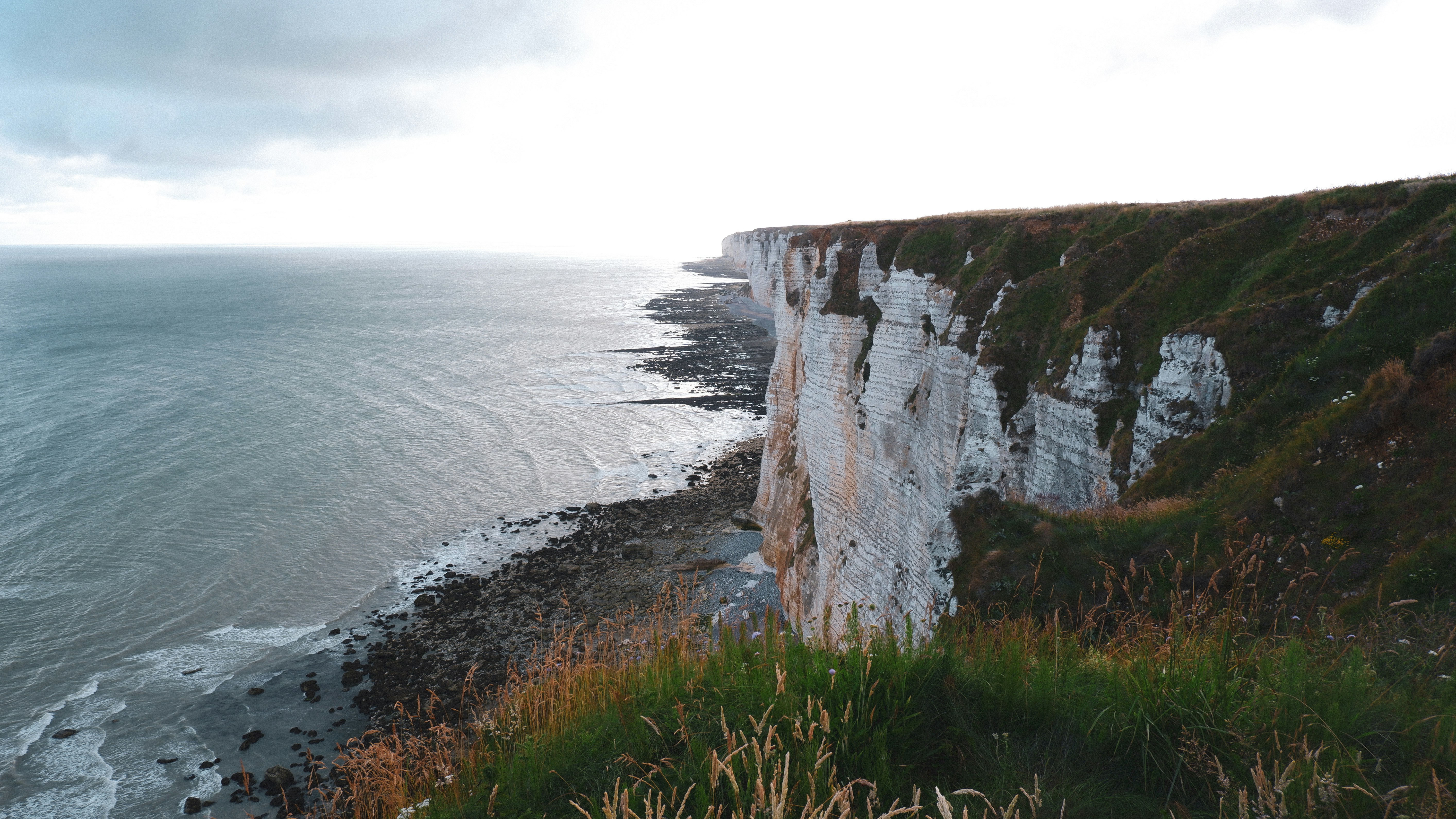 a cliff next to the ocean with Bempton Cliffs in the background