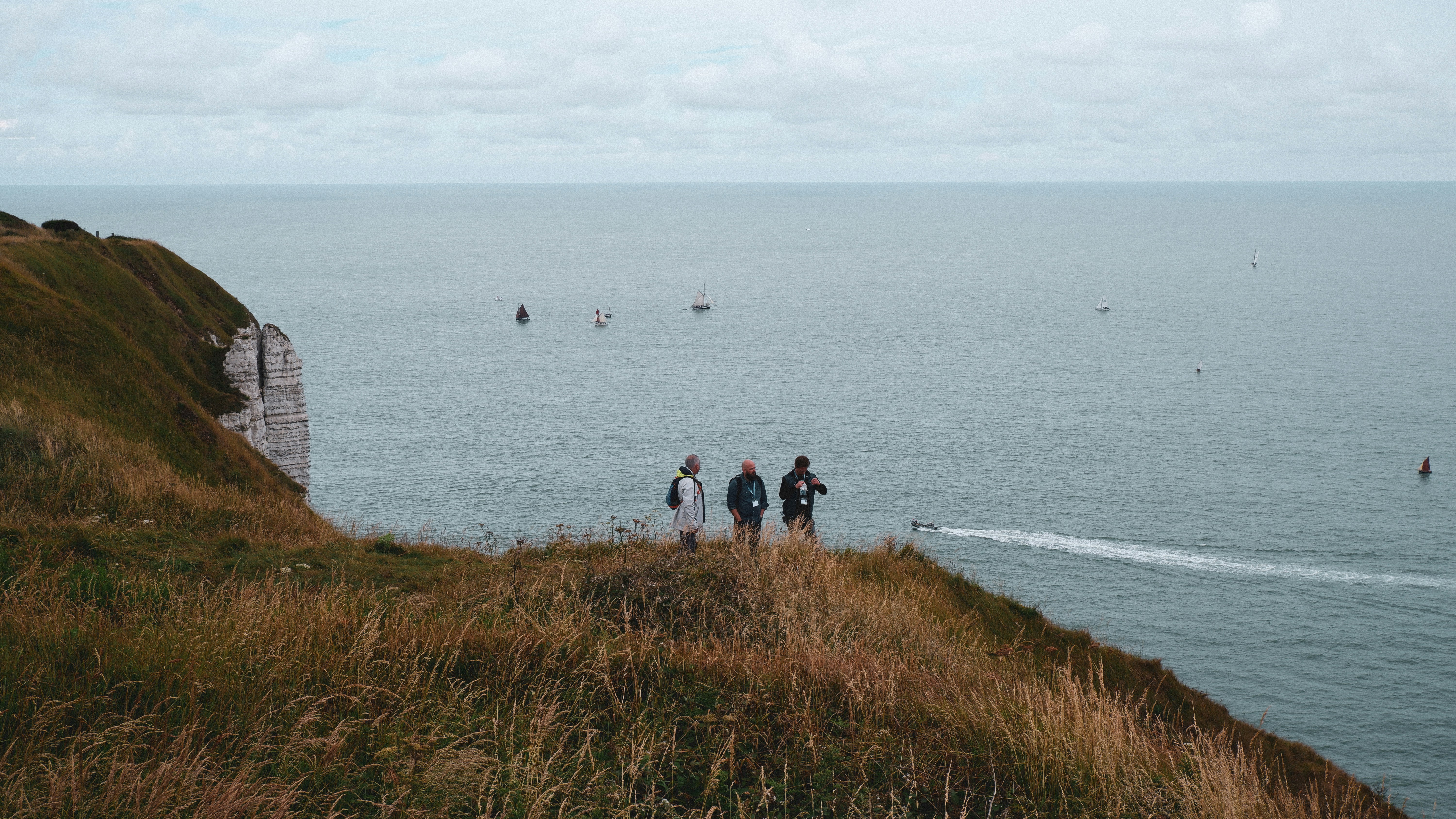 a group of people standing on a hill overlooking a body of water