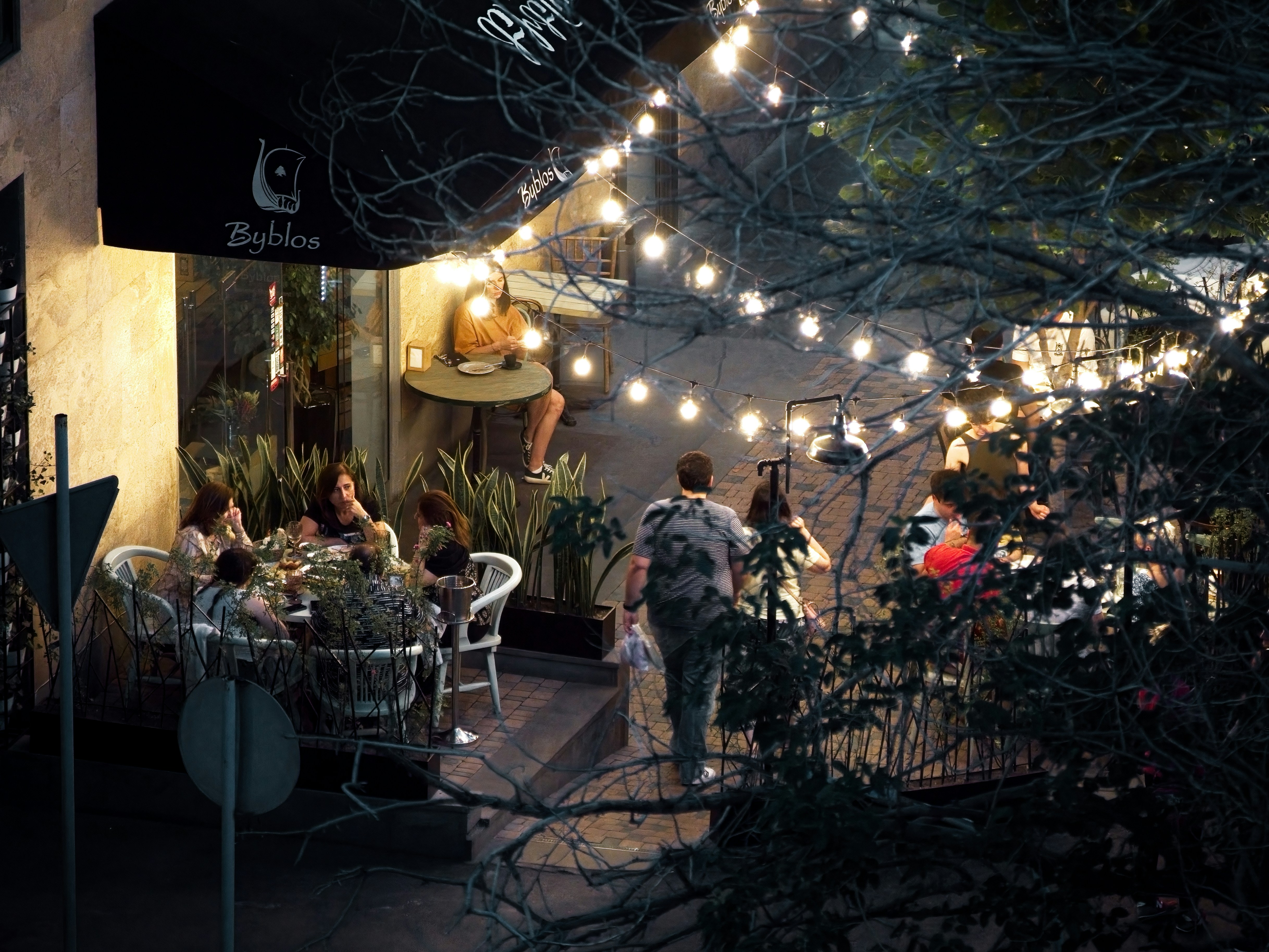 People at tables under string lights