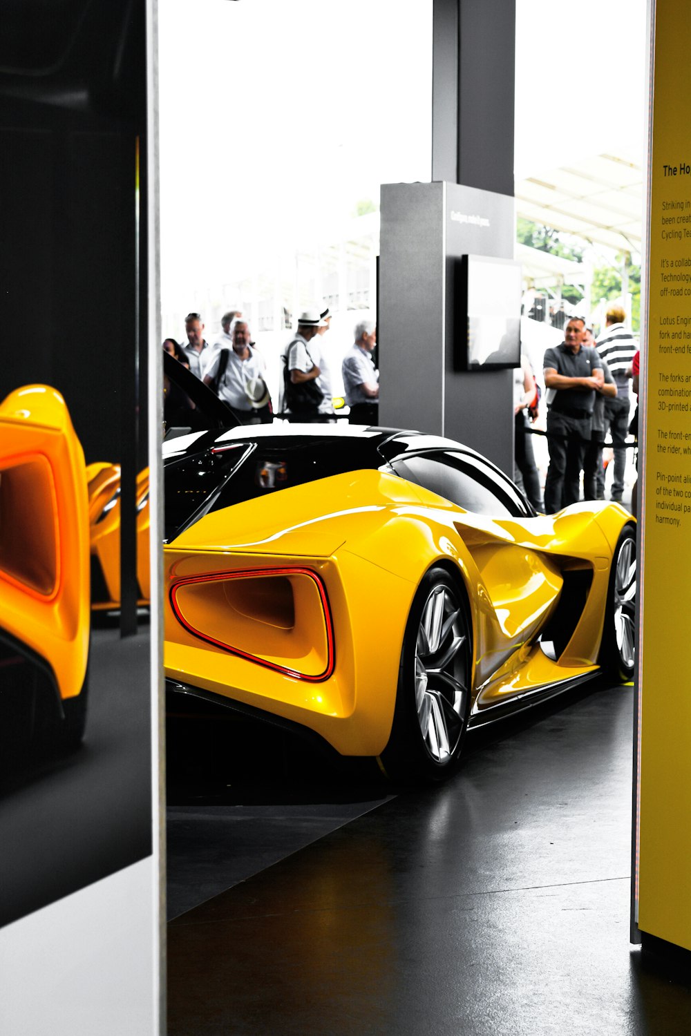 a yellow sports car in a showroom with people standing around