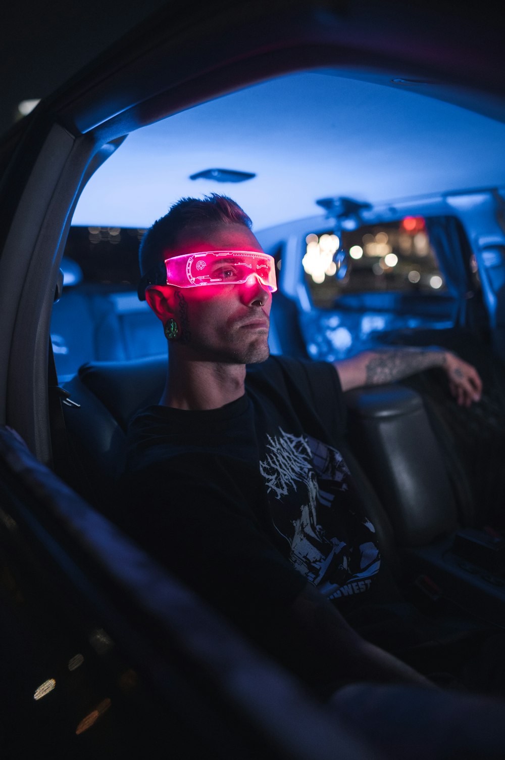 a man wearing red glasses and sitting in a car