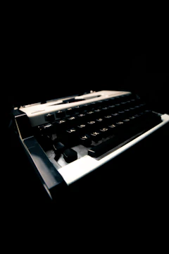 Close-up of a vintage typewriter with a black background and glowing keys