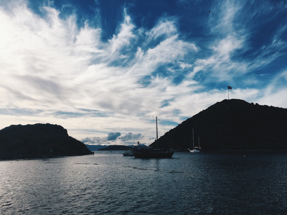 a body of water with boats and hills in the background