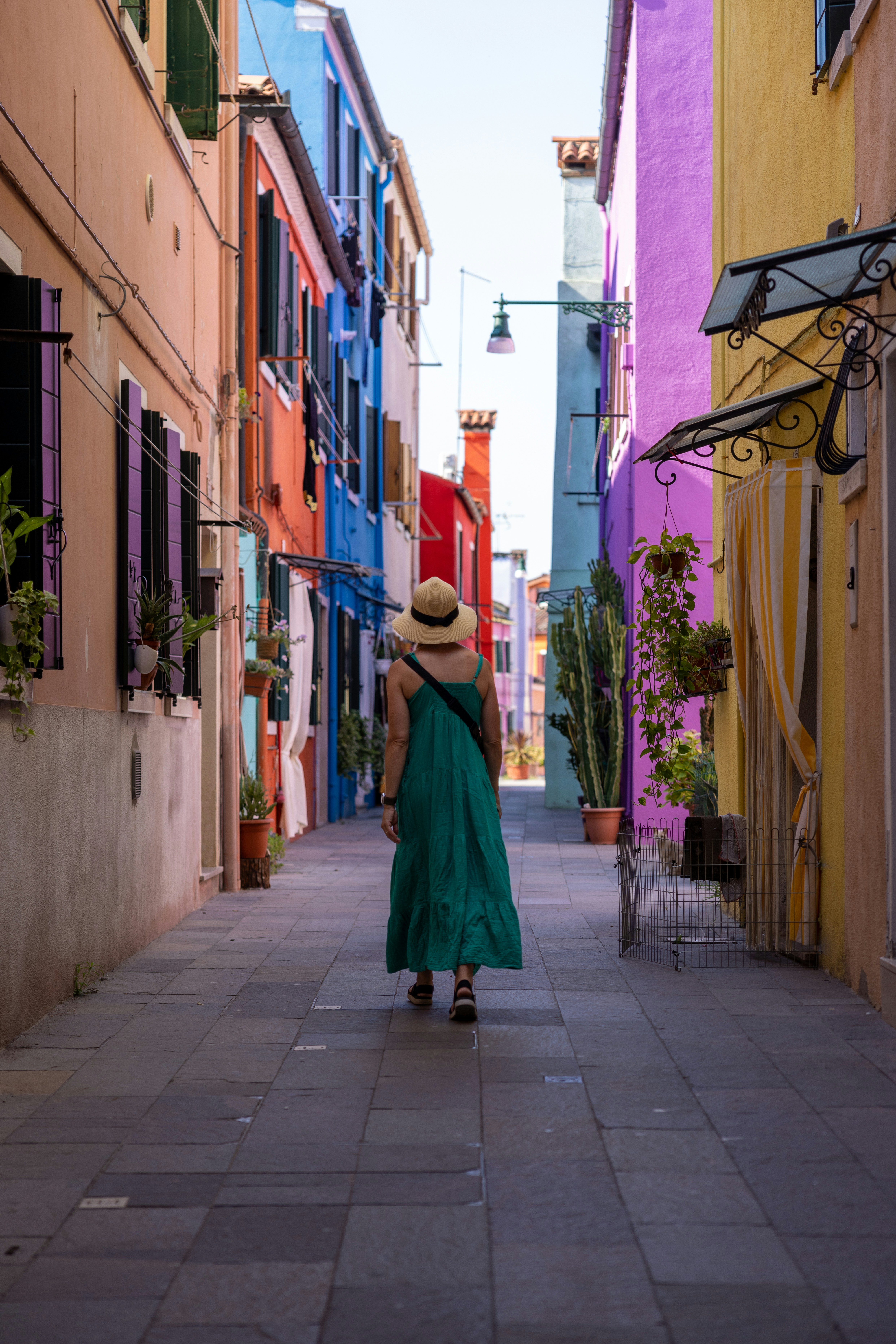 a person in a green dress walking down a narrow street lined with colorful buildings