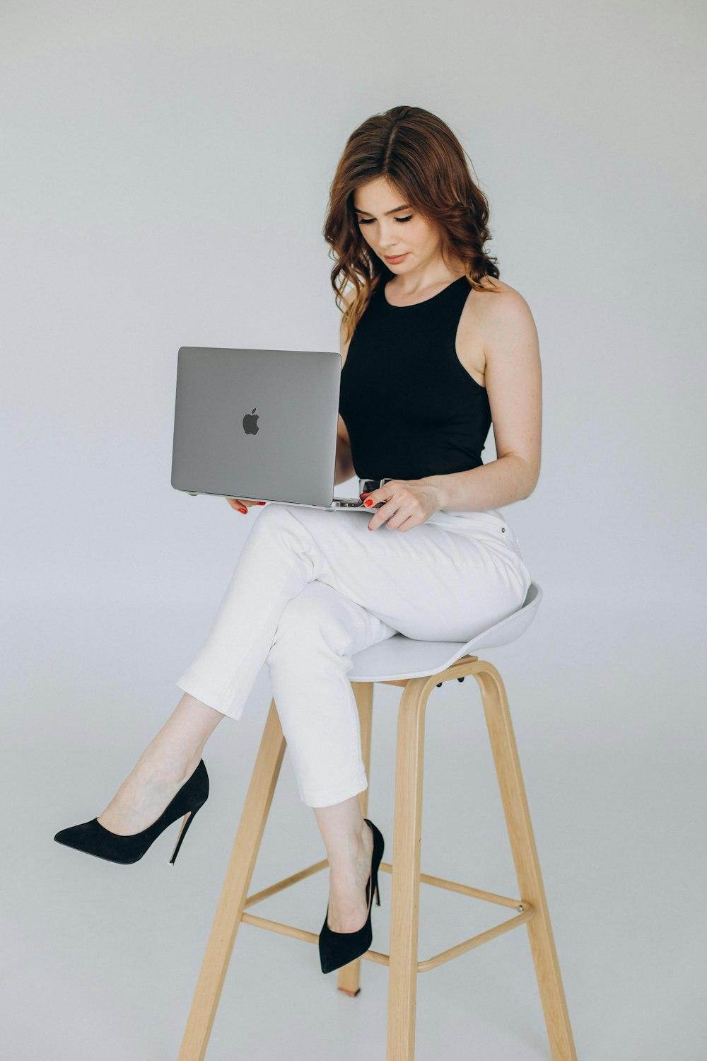 a woman sitting on a stool with a laptop