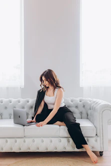 a woman sitting on a couch using a laptop