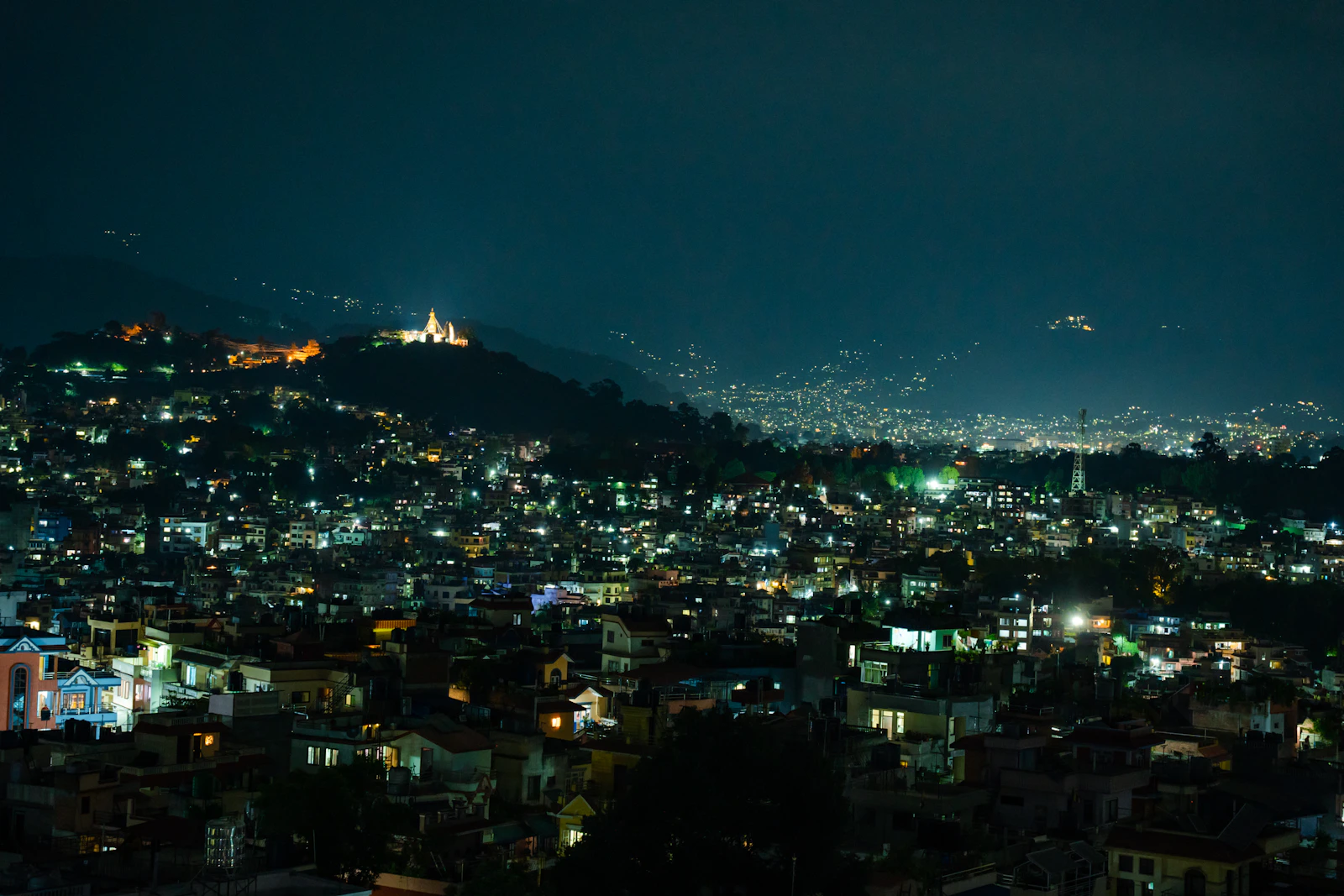 Kathmandu lit up at night from Kalanki, the city lights spreading to the hills and Swayambhunath glowing on its hilltop