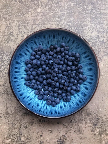 Close-up of a deep blue stoneware bowl with subtle texture, filled with fresh fruit.