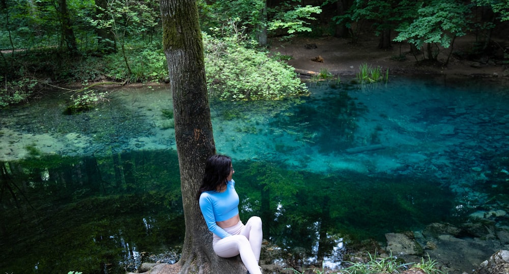 a person sitting on a rock by a body of water