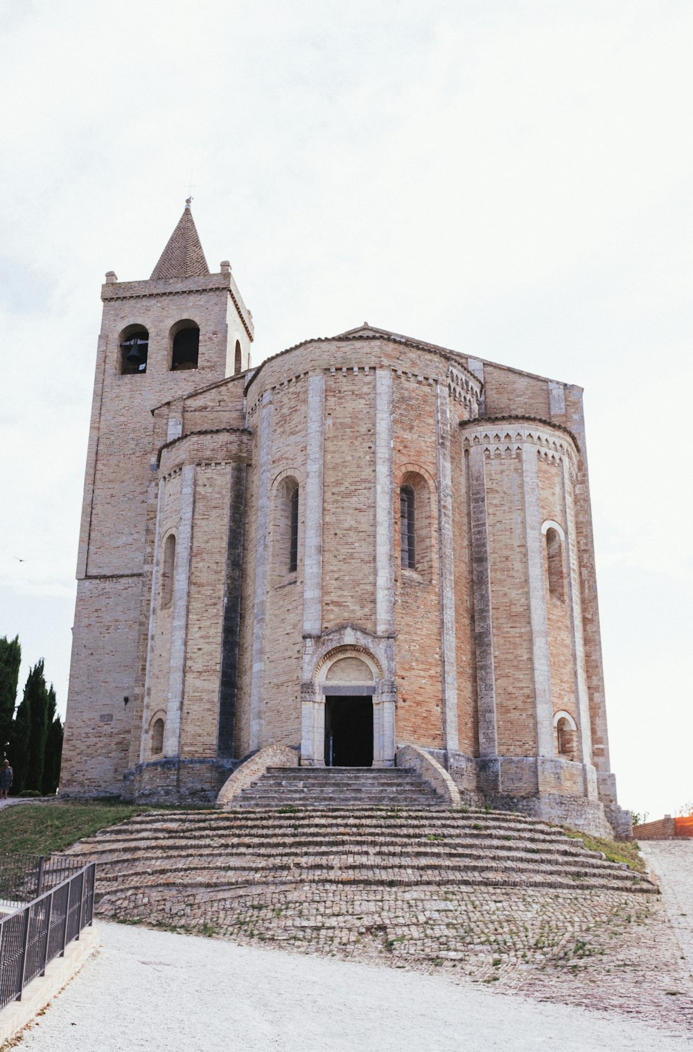 a stone building with stairs with Castle Rising in the background