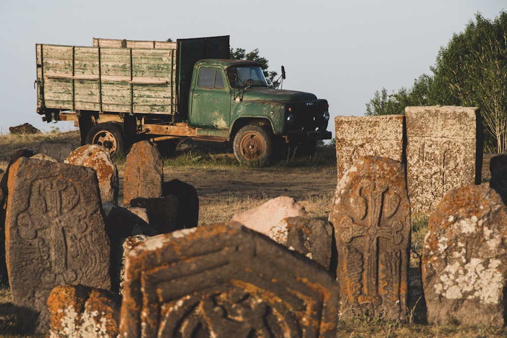 a green truck parked next to a pile of logs