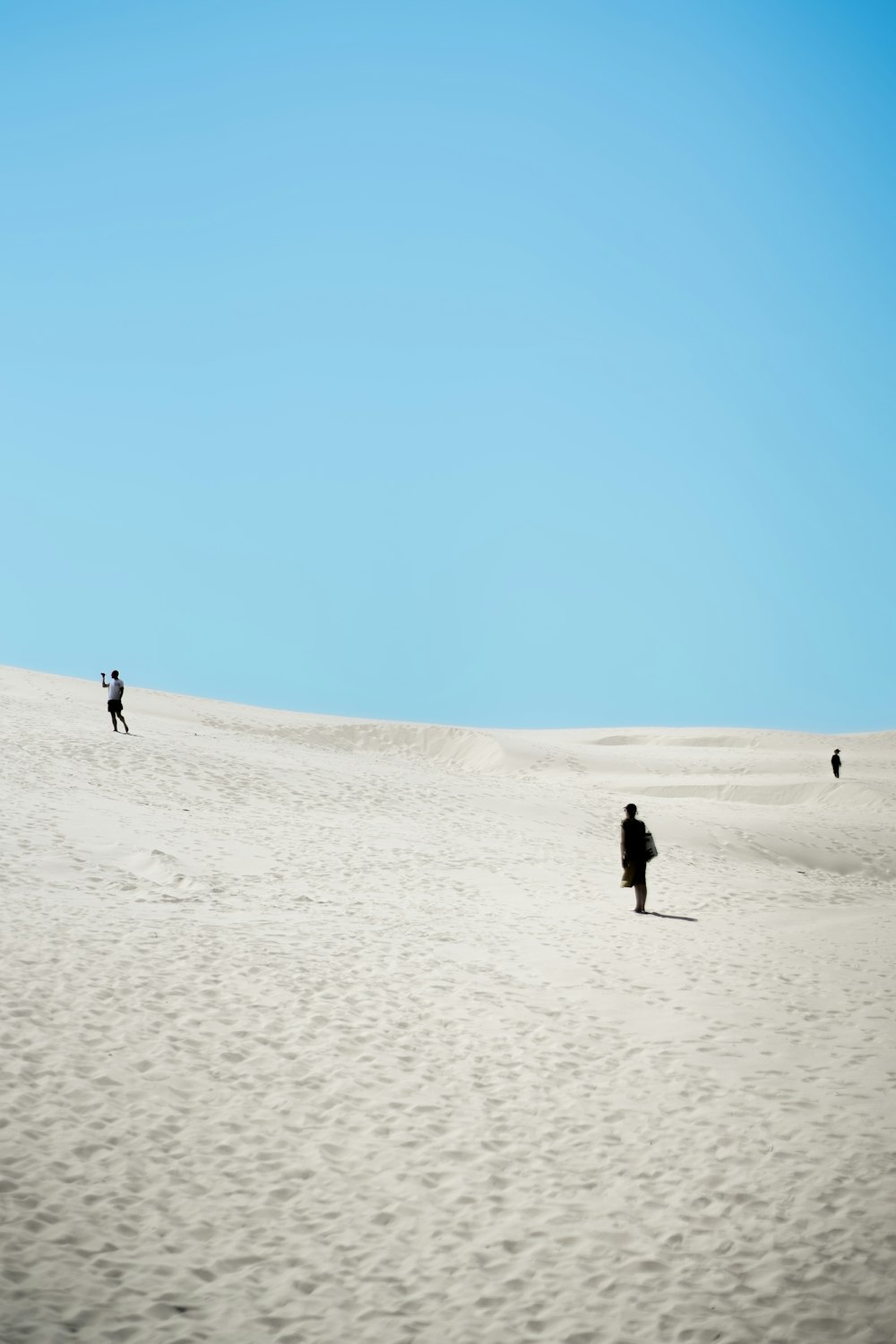 people walking on a sandy hill