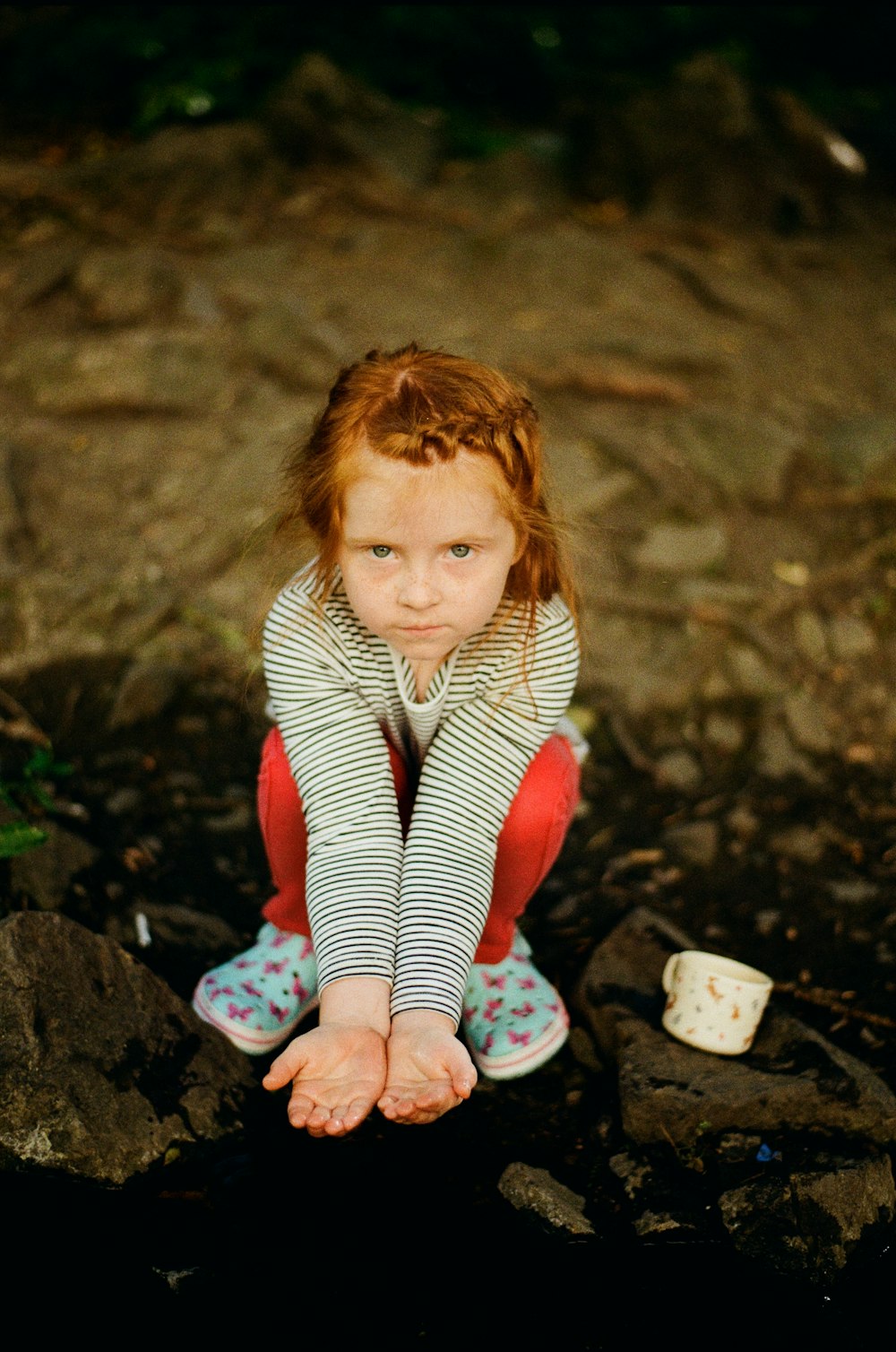 a little girl sitting on a rock