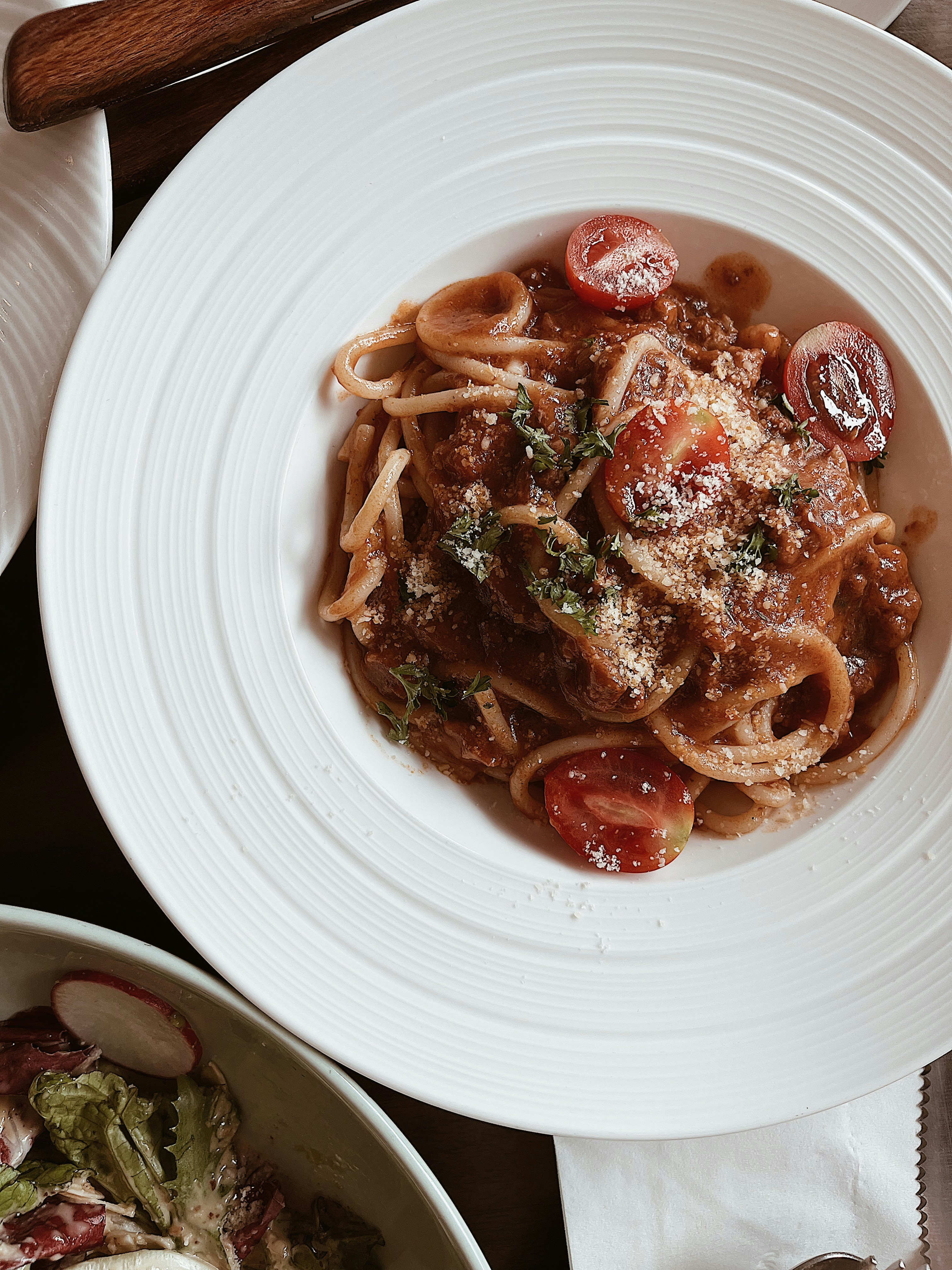 Beautifully plated pasta dish with rich sauce, fresh herbs, and parmesan, photographed on a white ceramic plate with warm side lighting