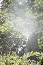 Close-up of a misting fan spraying cool mist at a lively outdoor party.