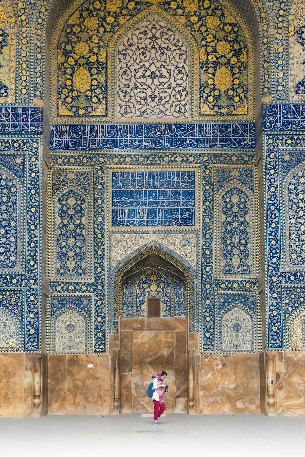 a person standing in front of a wall with intricate designs
