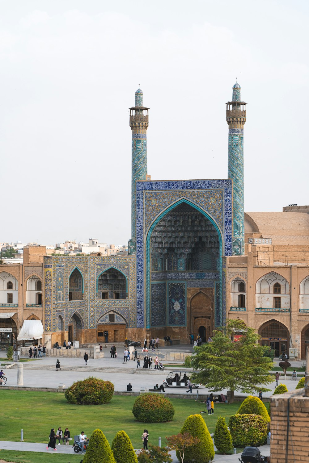 a large building with a green lawn and a large tower with Shah Mosque in the background