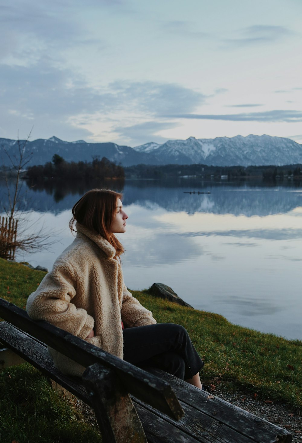 a person sitting on a bench looking at a lake