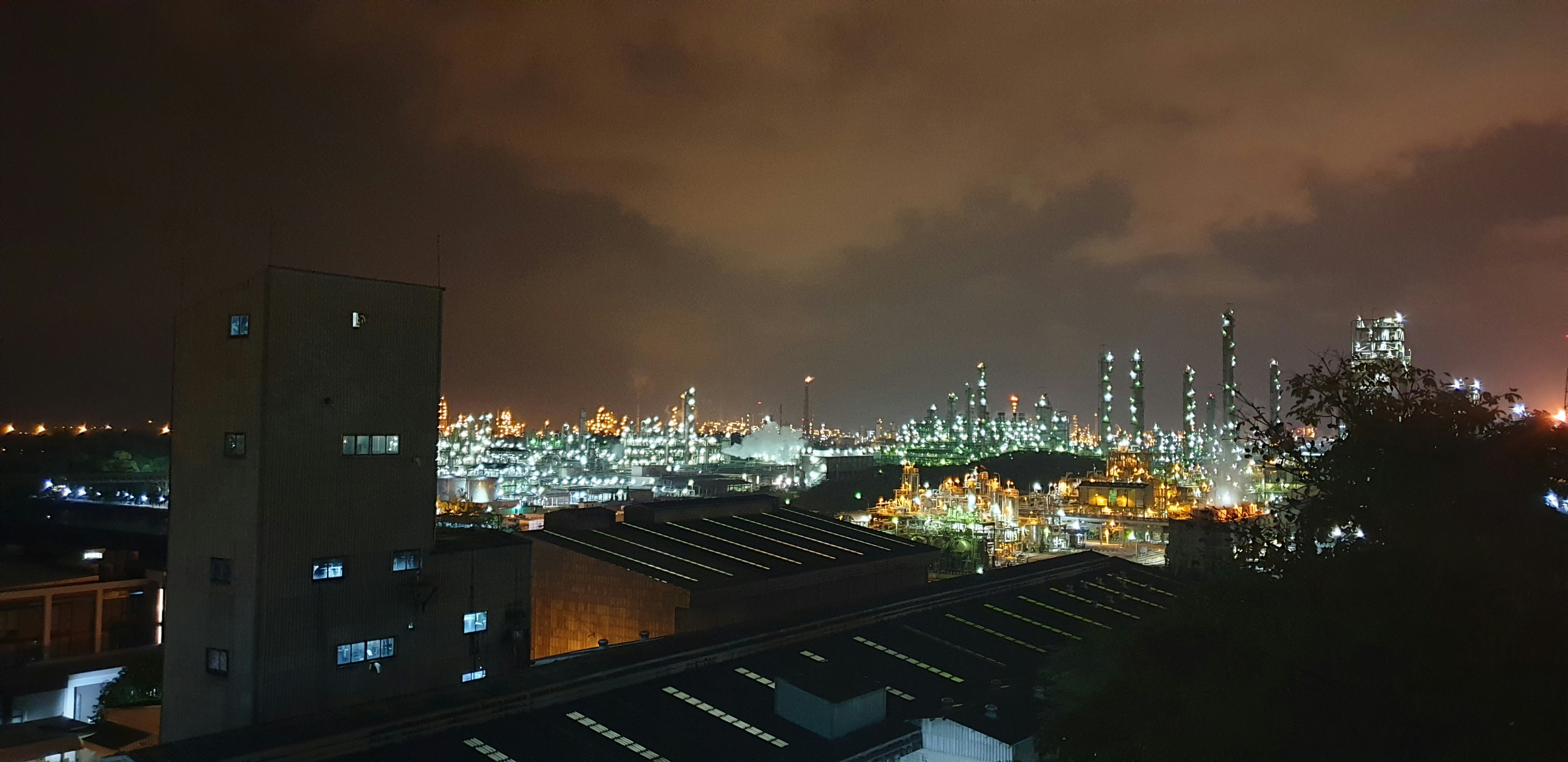 Oil refinery industrial complex at night, bright orange flare lights against dark sky