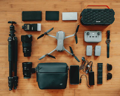 Close-up of drone accessories laid out on a sandy surface