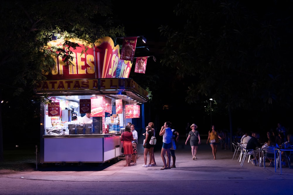 people walking past a food stand