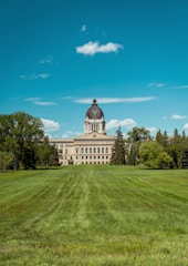 a large building with a dome and trees in the front