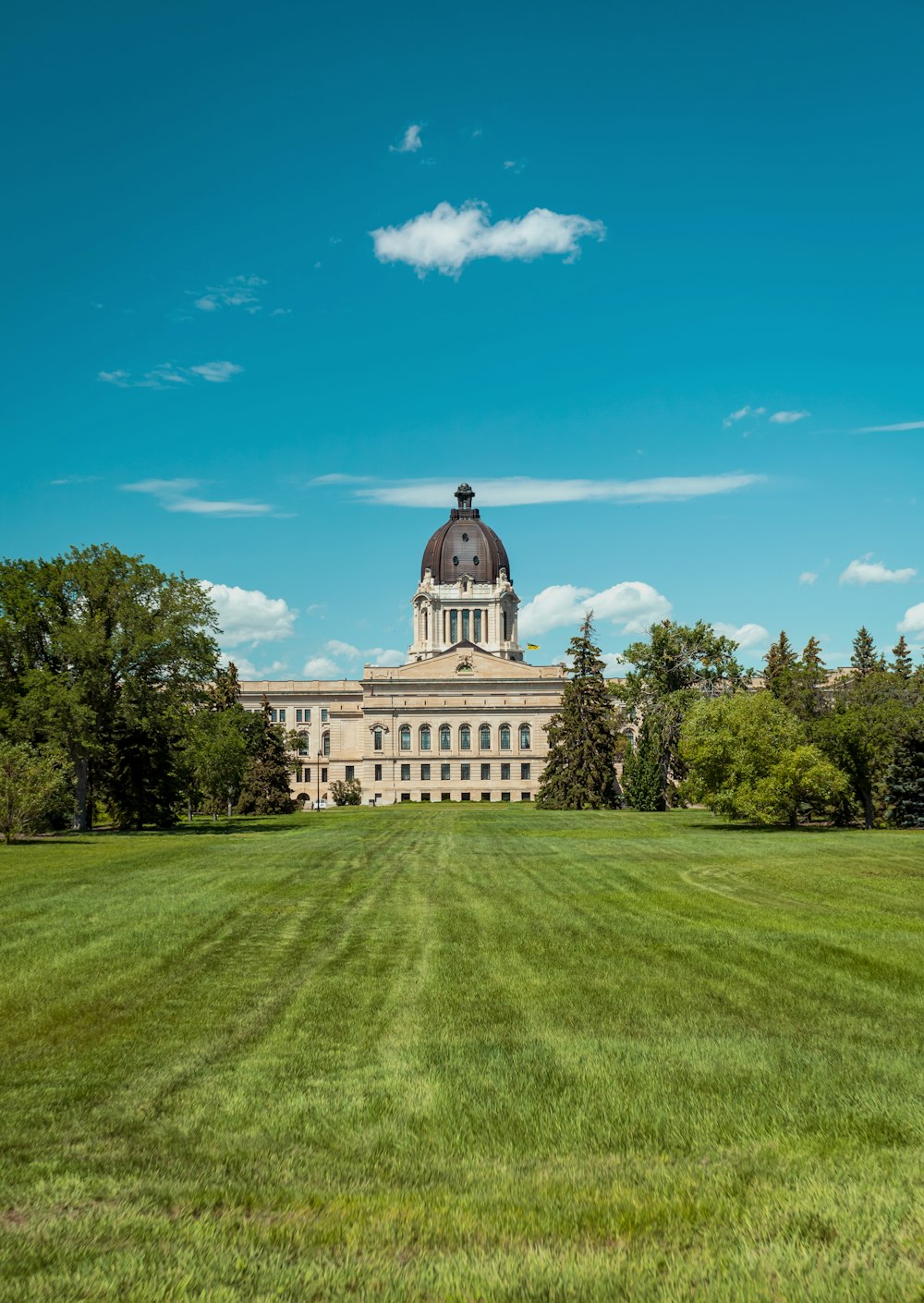 a large building with a dome and trees in the front