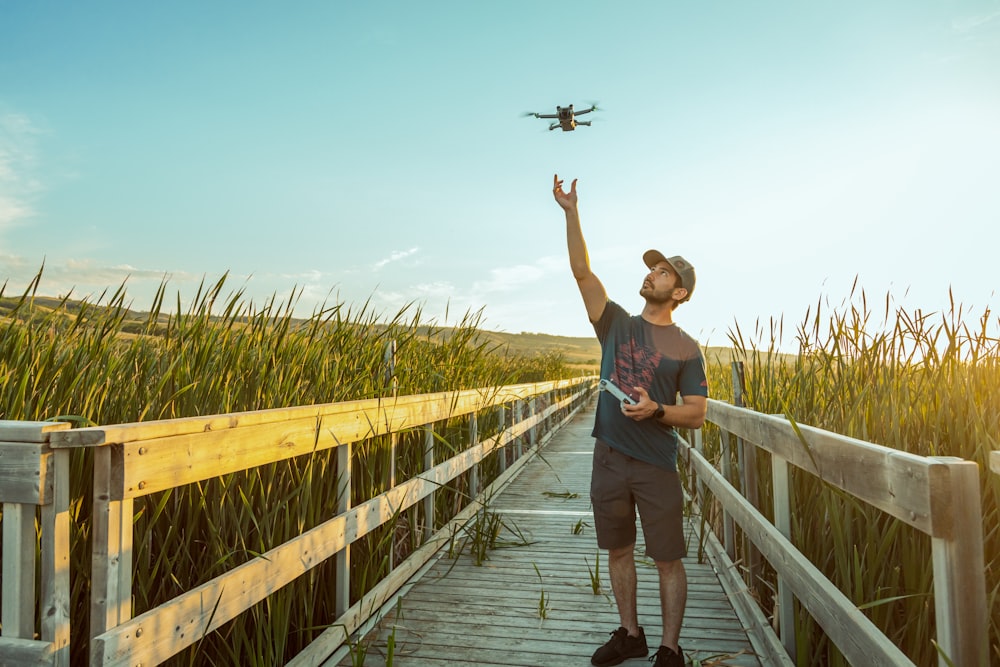 a man standing on a bridge with a plane flying in the sky