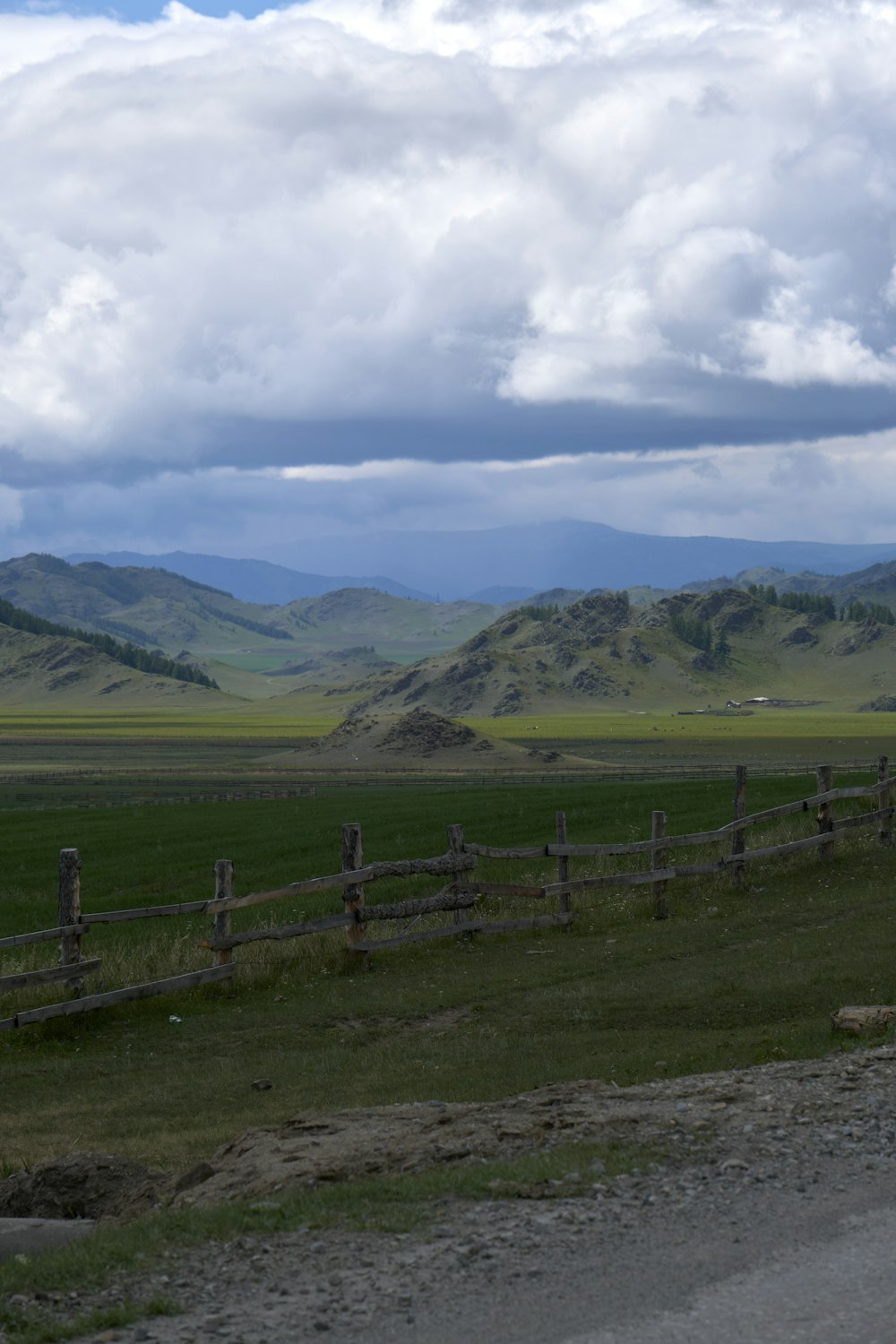 a fenced in field with a wooden fence and mountains in the background