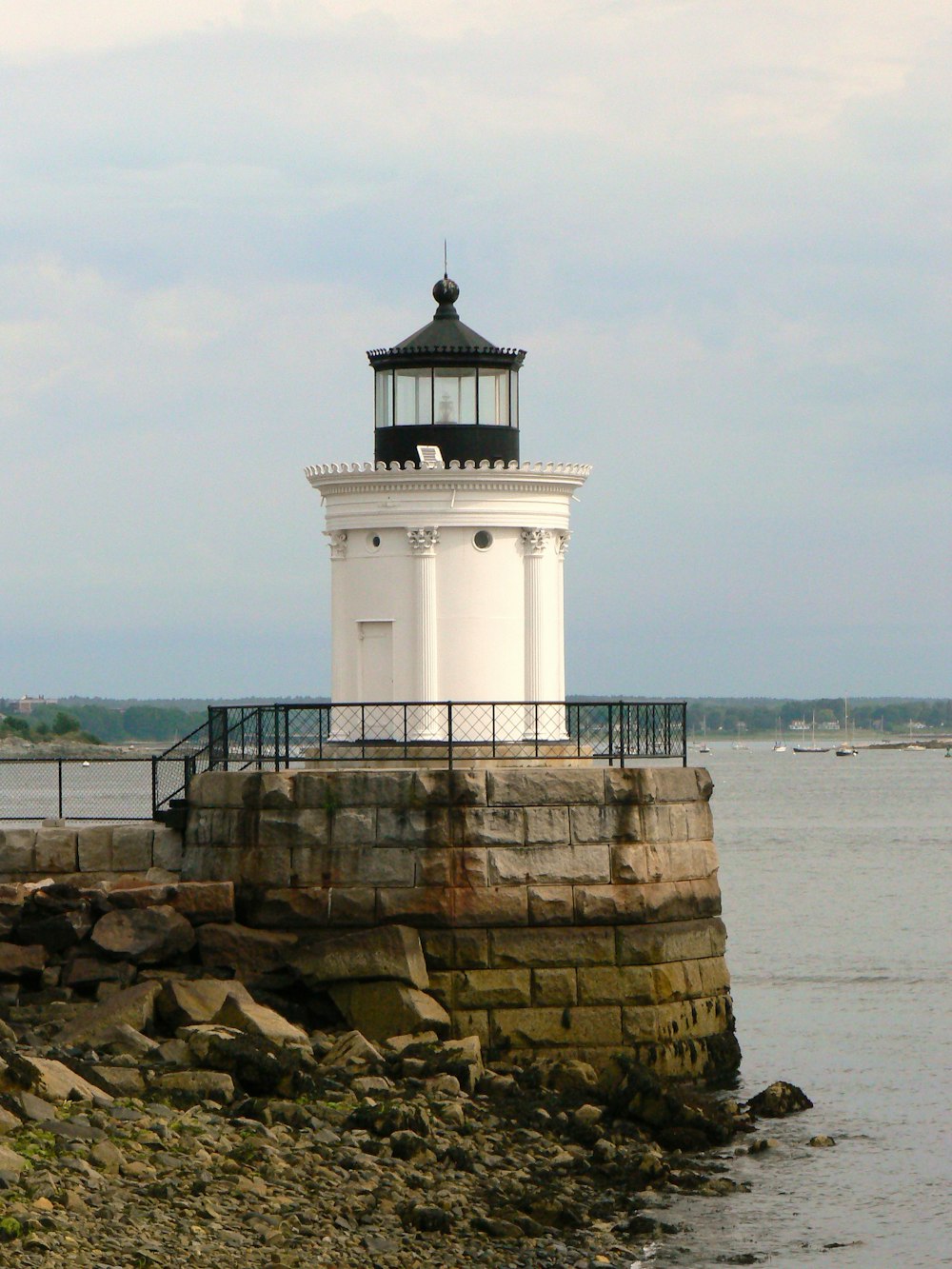 a light house on a rocky shore with Portland Breakwater Light in the background