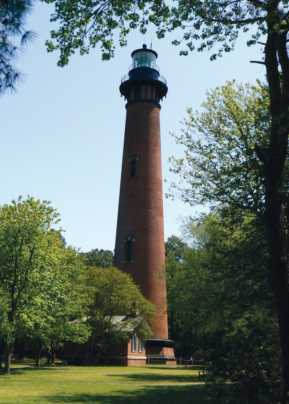 a tall tower with a light house with Currituck Beach Light in the background