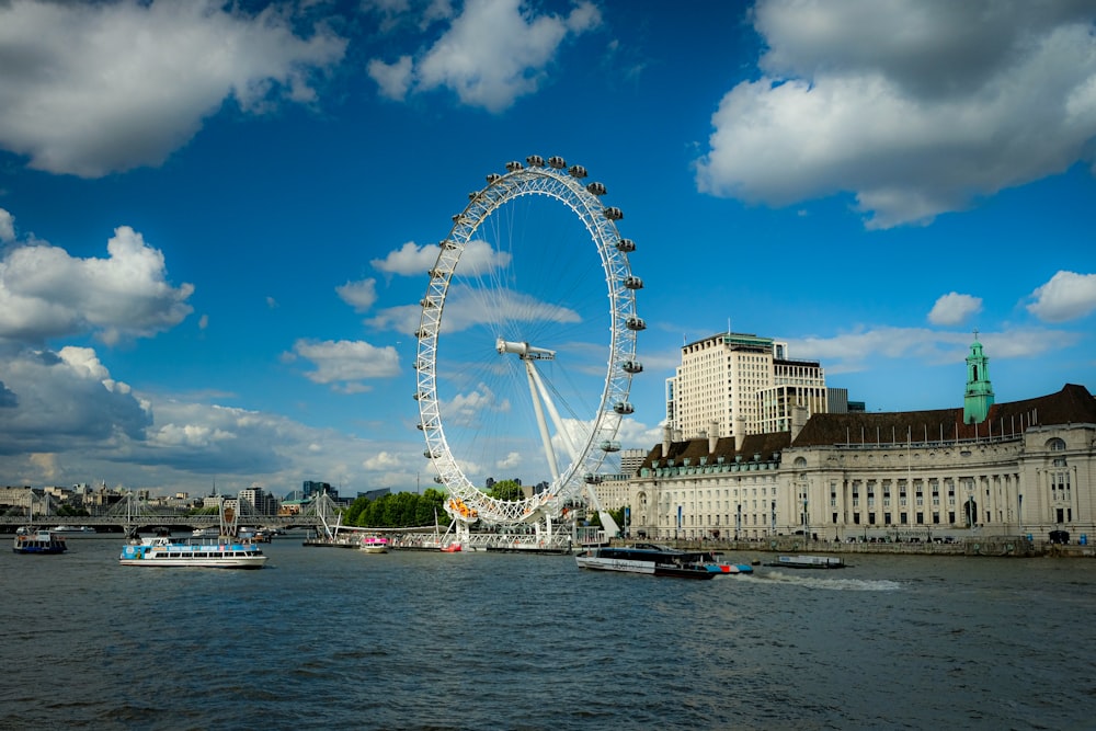 a ferris wheel by a body of water with London Eye in the background