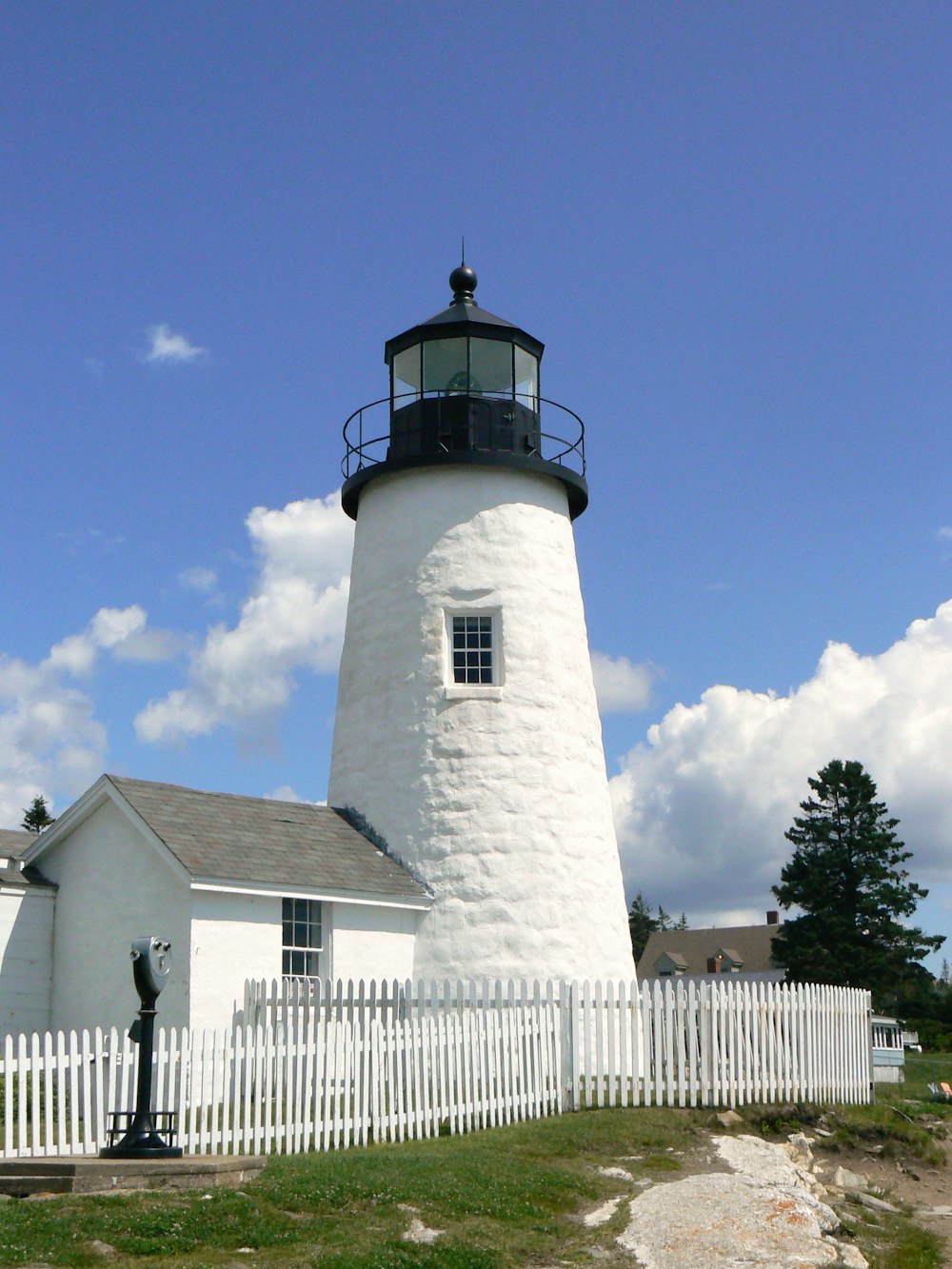 a white lighthouse with a white picket fence and a white picket fence